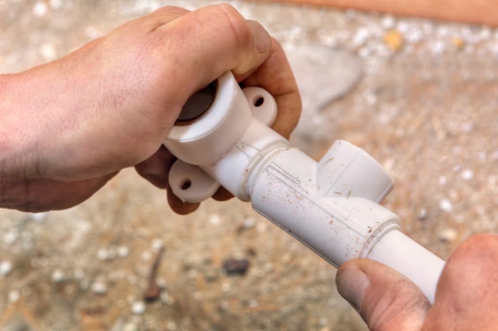 closeup of plumber's hands assembling pipes