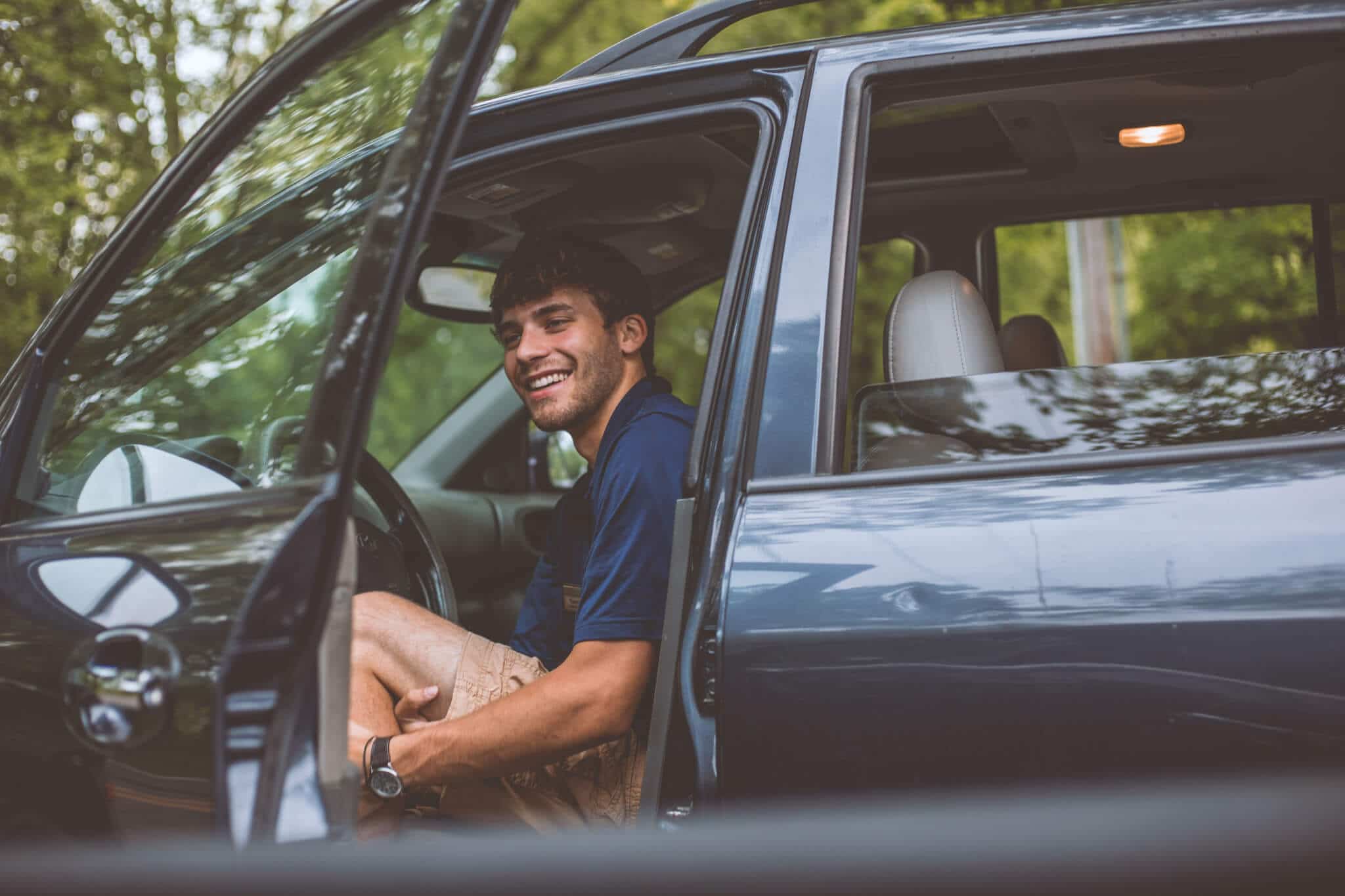 attractive man in front car seat with open door