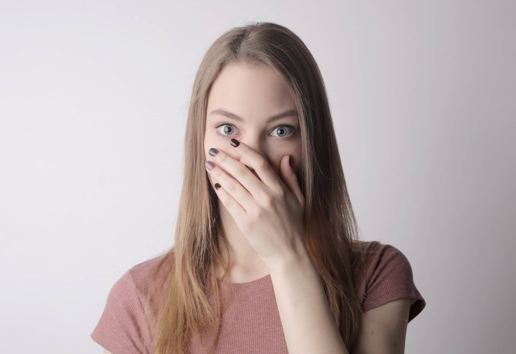 young girl covering her mouth