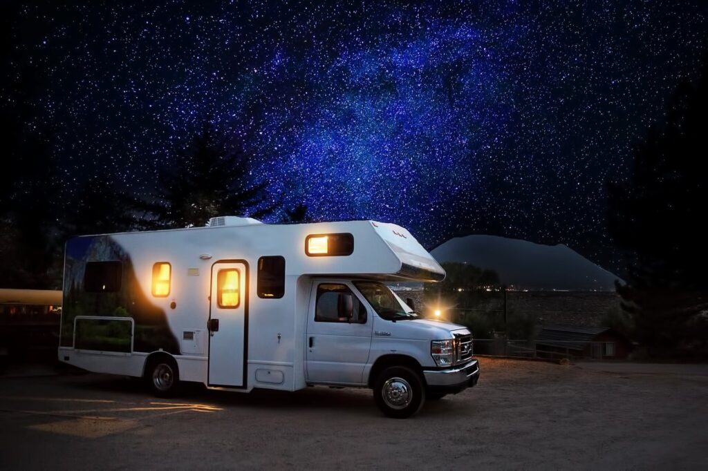 An RV trailer parked at a campsite at night.