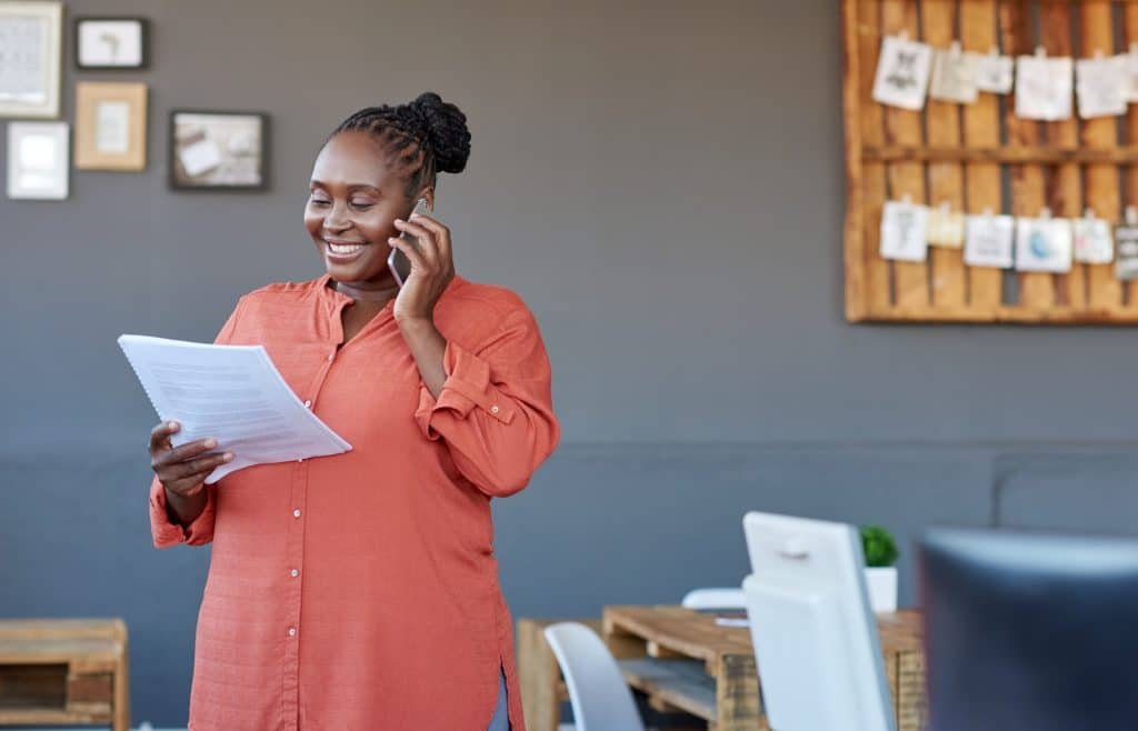 Smiling woman on phone with insurance agent while looking over contract