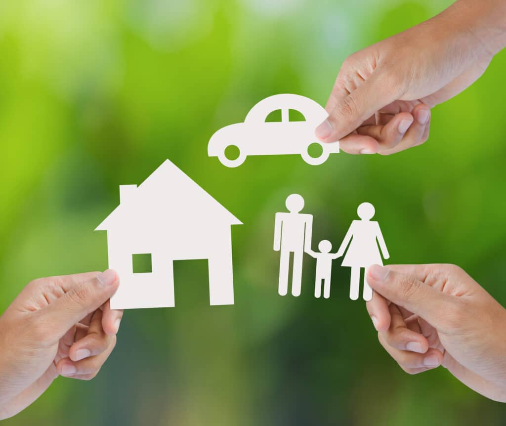 three hands holding paper cutouts of house, car, and family