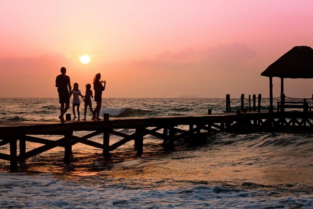 Family standing on beach pier at sunset
