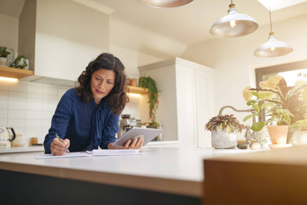 A woman sitting in her kitchen reviewing her life insurance documents.