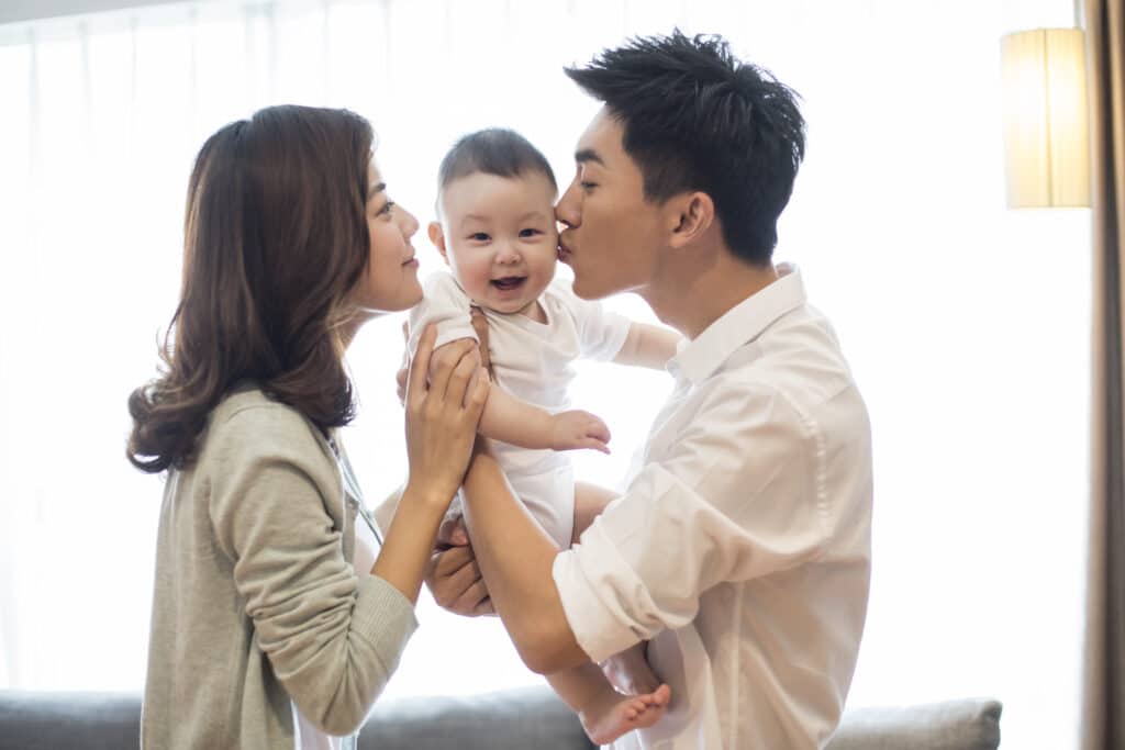 parents kissing baby on cheek