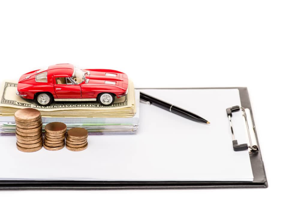 toy red car on top of money and clipboard