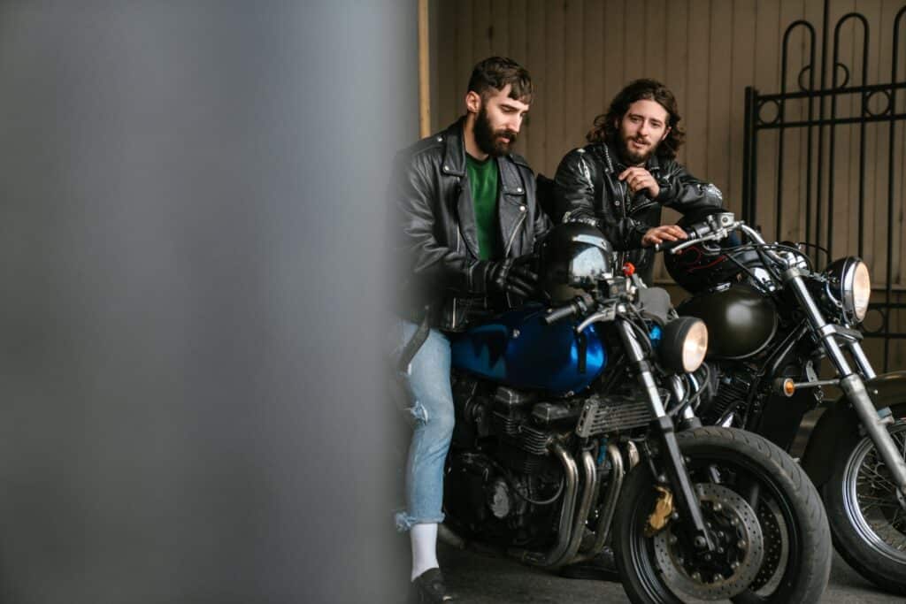 two men sitting on motorcycles side by side