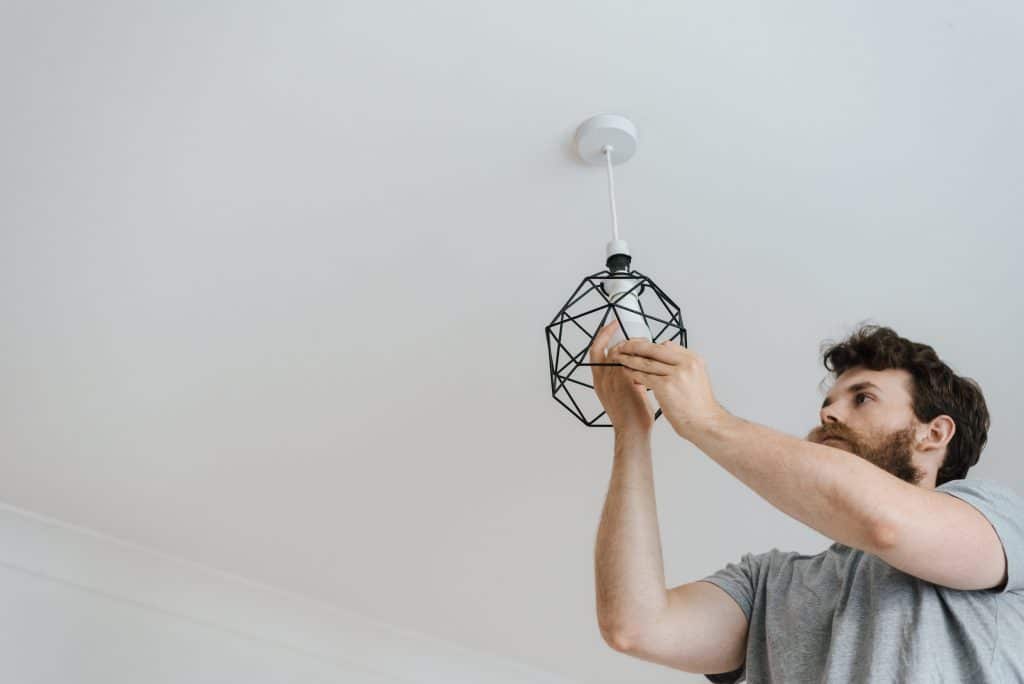 man installing light fixture