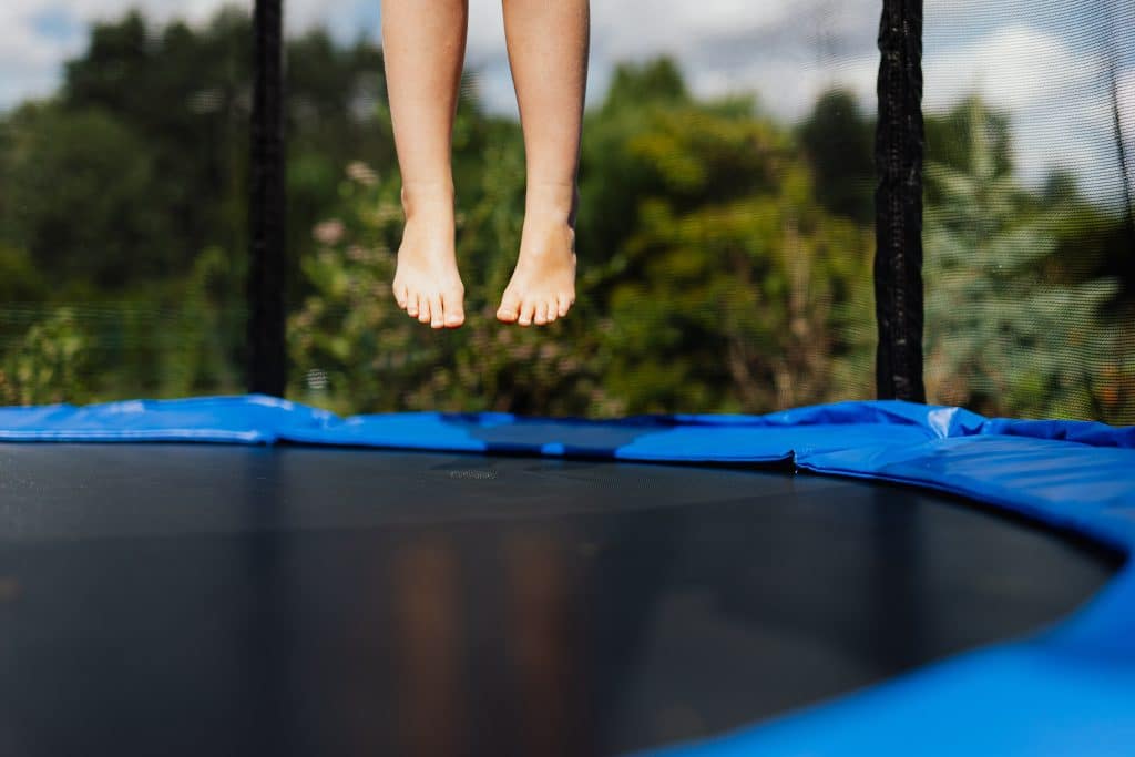closeup of feet of person jumping on trampoline