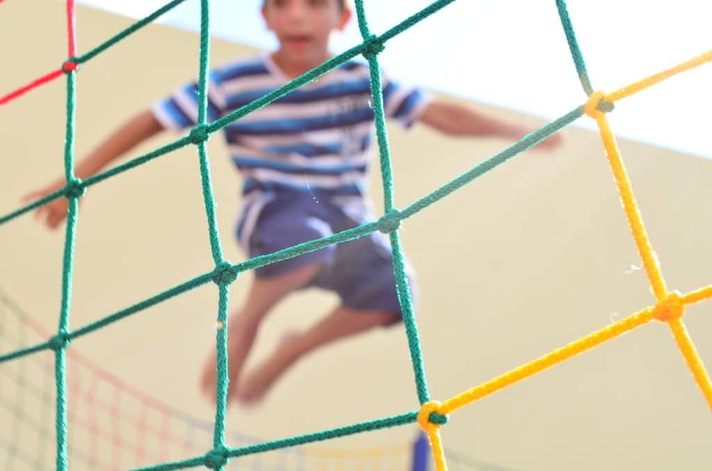 focus on trampoline net with image of blurred boy in mid jump in the background