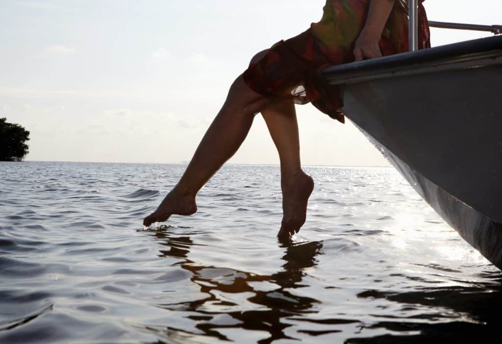 woman sitting on edge of motorboat with feet in water
