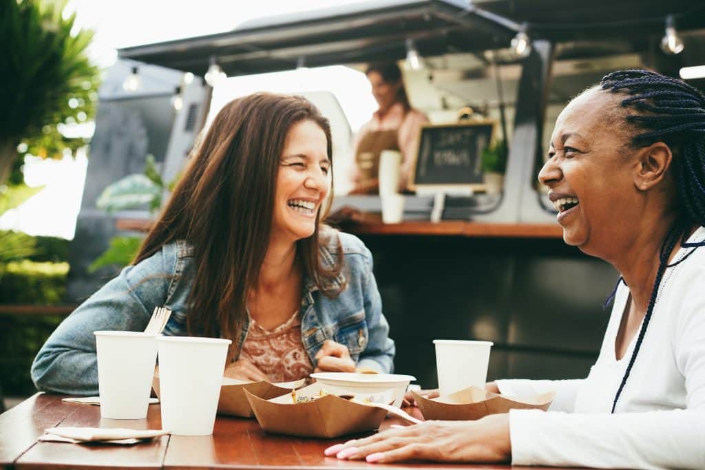 Laughing women eating outside a food truck
