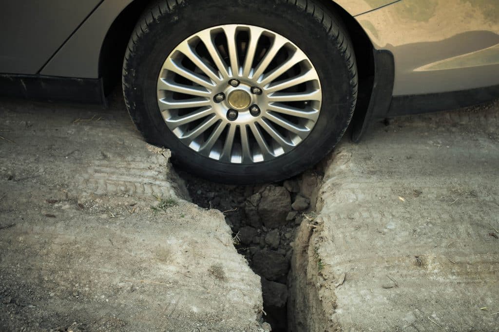 Closeup of car tire stuck in large pothole