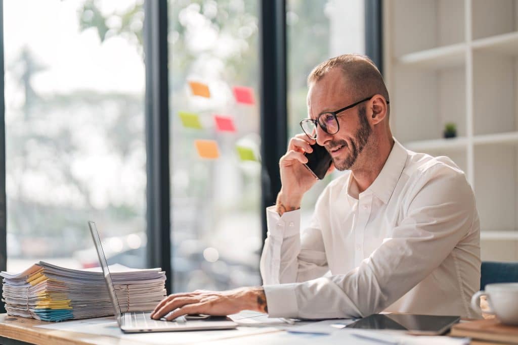 Businessman using laptop computer in office. Happy middle aged man, entrepreneur, small business owner working online...